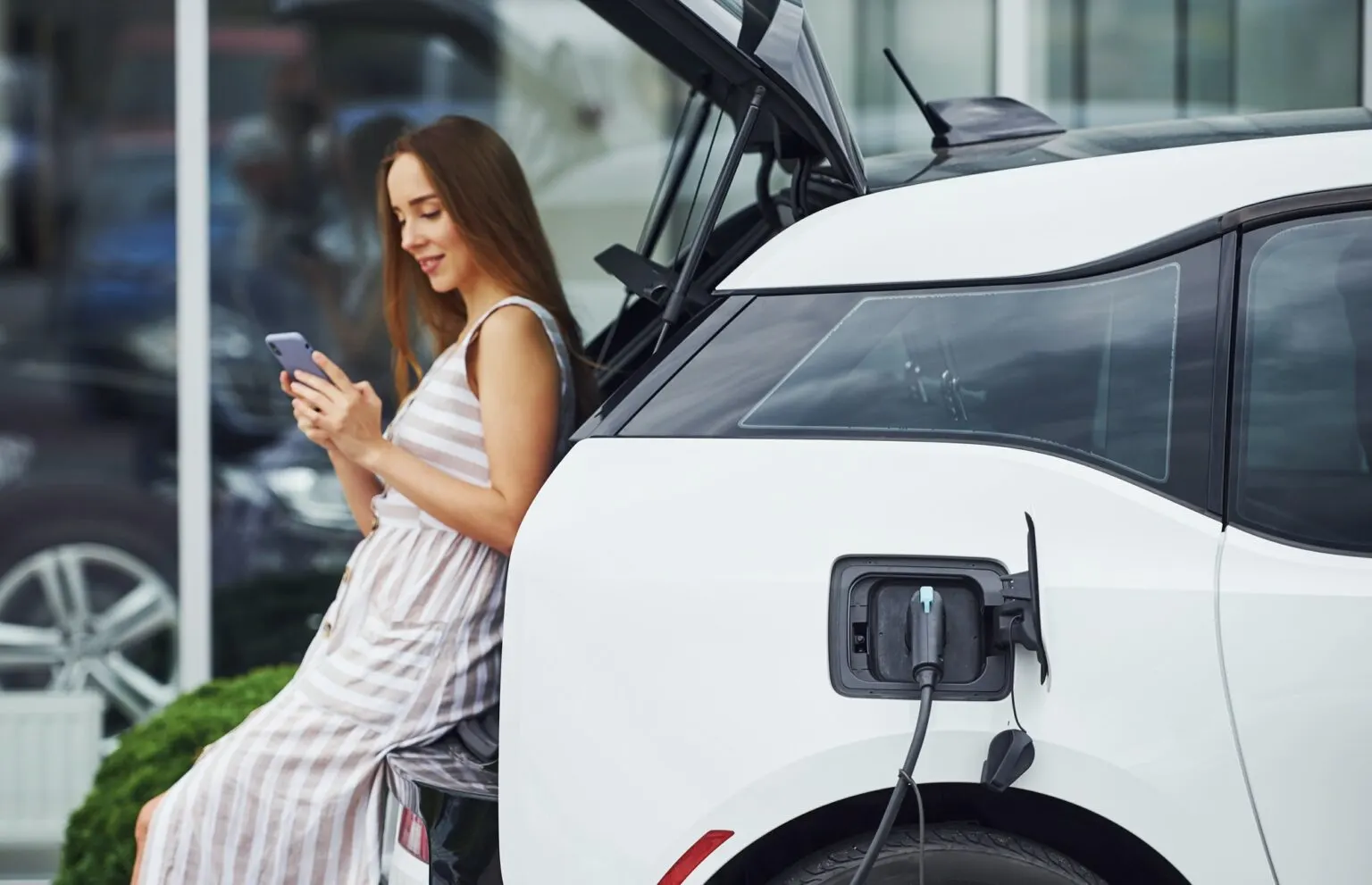 woman-on-the-electric-cars-charge-station-at-daytime-brand-new-vehicle-1536x991